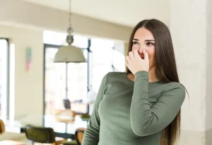 Nainen pitää nenästään kiinni, kun haistaa pahan hajun